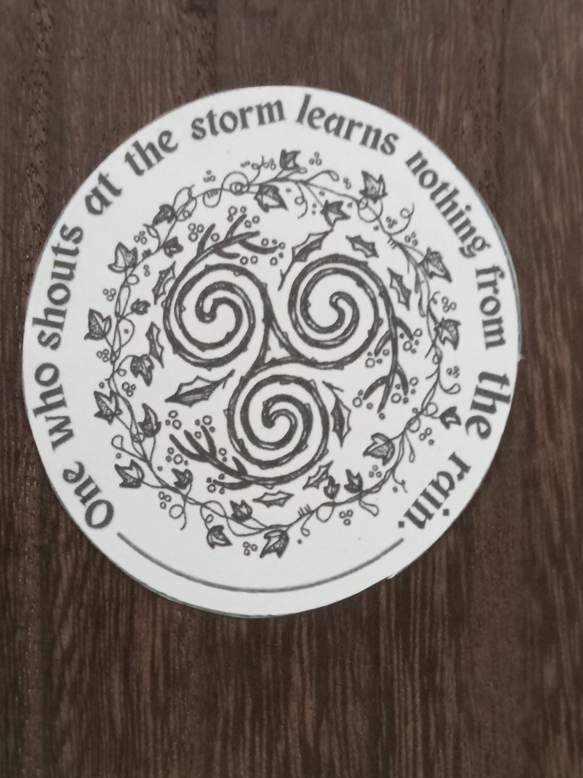 Circular sticker with design and text on a wooden surface