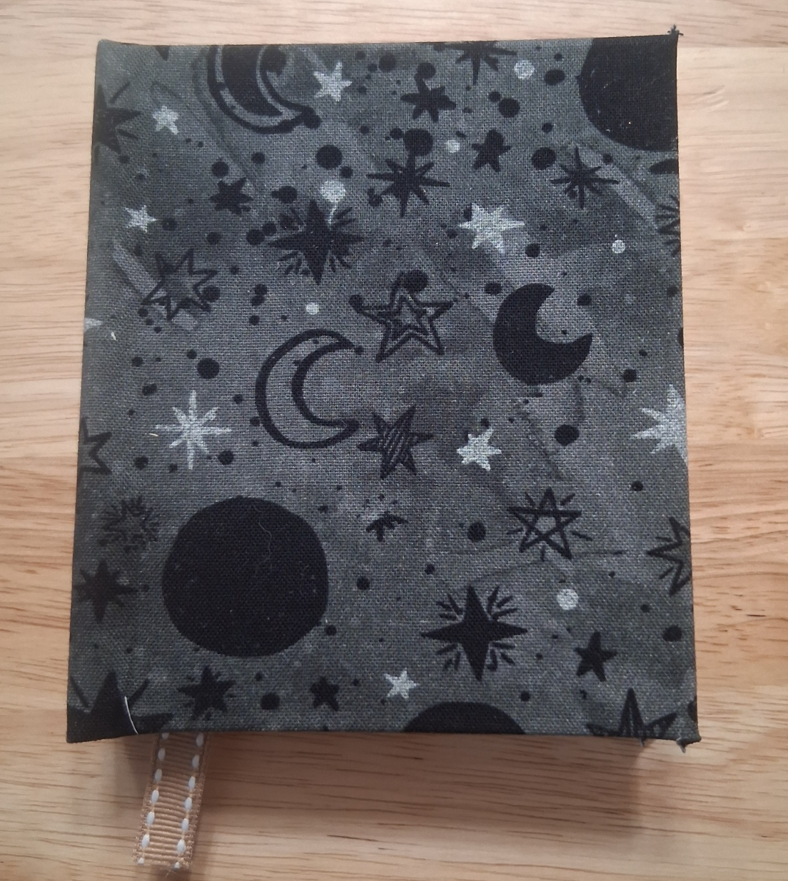 Front of small gray handmade journal with black moons and black and silver-toned stars