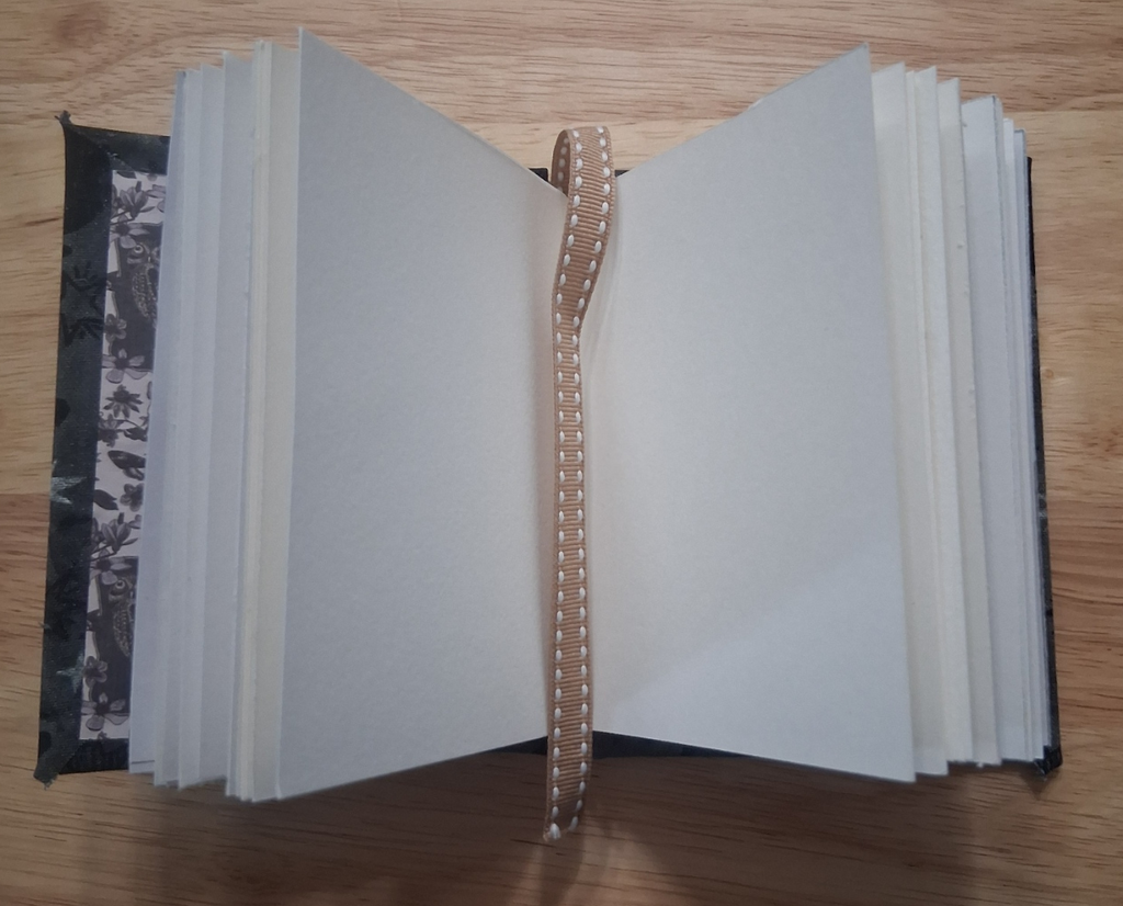 Blank mixed-media pages and ribbon bookmark inside small handmade journal