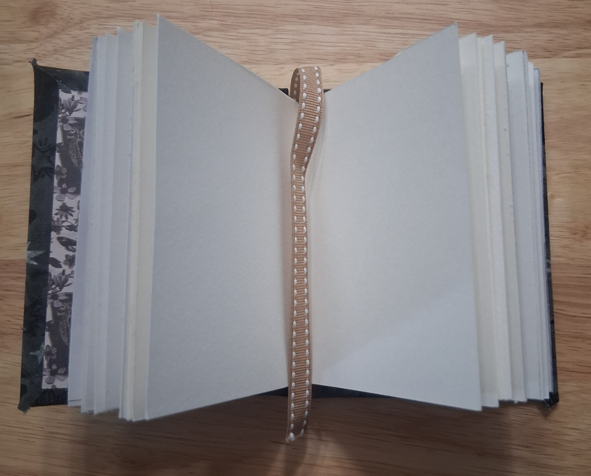Blank mixed-media pages and ribbon bookmark inside small handmade journal